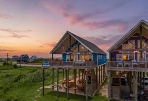 a house with a wrap around deck at sunset at Spacious Beachfront 5BR with Gorgeous Ocean views - Blue Footed in Bolivar Peninsula