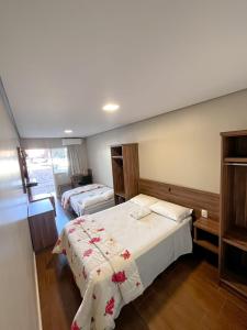 a hotel room with two beds and a window at Hotel Ponto 1 in Vacaria