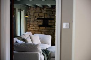a living room with a white couch and a brick wall at Rose Cottage - Sands Farm in Wilton