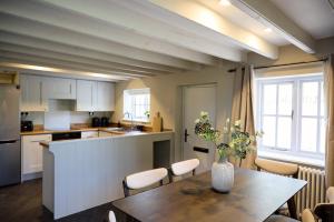 a kitchen with a table with a vase of flowers on it at Rose Cottage - Sands Farm in Wilton