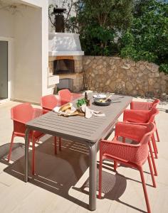 a patio table with red chairs and a fireplace at Aparatment house Gloss Primosten in Primošten