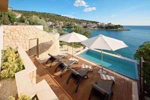 a swimming pool with chairs and umbrellas next to the water at Aparatment house Gloss Primosten in Primošten +42 photos