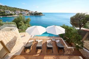 a table and chairs with umbrellas and the ocean at Aparatment house Gloss Primosten in Primošten
