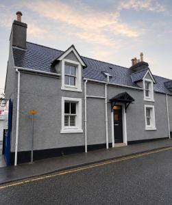 a gray house with a black roof on a street at The townhouse in Stornoway