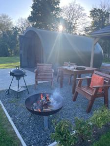 a fire pit with a picnic table and a grill at Kinelarty Luxury Glamping Pods Downpatrick in Downpatrick
