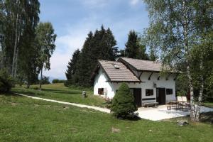 a small white house in a field with trees at Casera Marisa Nevegal in Nevegal