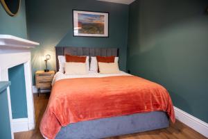 a bedroom with a large bed with an orange blanket at The Nook in Claypits