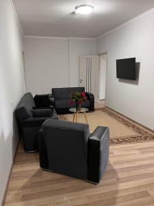 a living room with black couches and a tv at Apartament modern cu dormitor separat si balcon panoramic in Căuşeni