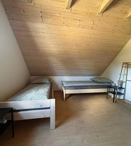 a attic room with two beds and a ladder at Za Bocianami- domki w Bartoszymlesie in Stara Kiszewa