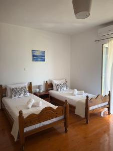 two beds in a room with white walls and wooden floors at M & A Ionian Balcony in Himare