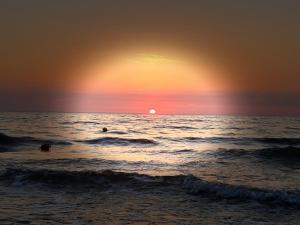 two people swimming in the ocean at sunset at Dom Rybaka Bobolin in Bobolin