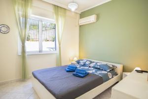 a bedroom with a bed with blue sheets and a window at Ξενώνας της Αγάπης in Salamina +16 photos