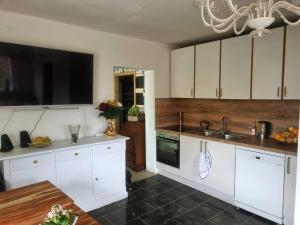 a kitchen with white cabinets and a sink and a table at Bauernhof Privatzimmer Frei WiFi Gemeinschaftsbad in Hausbreitenbach