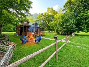 a cabin with chairs and a fire in the yard at River Dreaming in Townsend