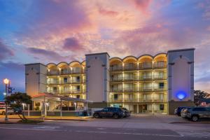a building with cars parked in a parking lot at SureStay Hotel by Best Western Virginia Beach Royal Clipper in Virginia Beach