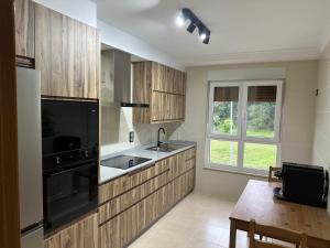 a kitchen with wooden cabinets and a black appliance at Pilgrims House II in Lourenzá