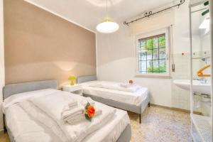 two beds in a room with a shower and a sink at Villa Panorama with Private Pool in Nago-Torbole