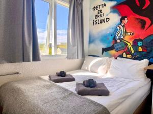 a bed with two pillows on it with a painting on the wall at The Stykkishólmur Inn by Ourhotels in Stykkishólmur