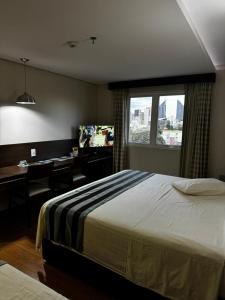 a bedroom with a bed and a desk and a window at Hotel Maestro Premium Cascavel in Cascavel +50 photos
