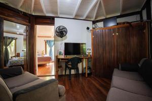 a living room with a couch and a desk with a television at Bungalows Aché Cahuita in Cahuita