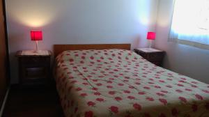Un dormitorio con una cama con flores rojas. en Departamento Tacuarí en San Carlos de Bariloche