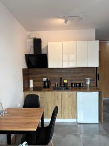 a kitchen with white cabinets and a table and chairs at SWP Plac Solny 4 z klimatyzacją in Głogów
