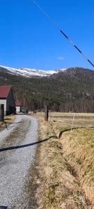 an empty road in a field with a house and a fence at Romantic farmhouse in Vaksdal