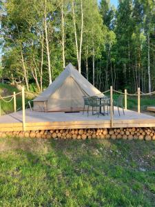 a tent with a table and a bench on a wooden deck at Glamping Tolvsbo Inn in Söderbärke