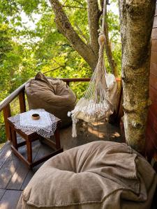 a porch with a hammock and a table and a tree at Eagle Park&Camping in Bajkaj
