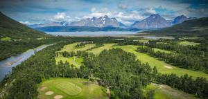 an aerial view of a golf course with a river and mountains at Mountainside Lodge - Breivikeidet in Tromsø