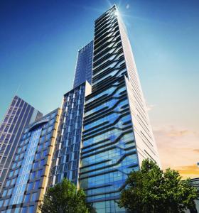 un grand bâtiment en verre avec des arbres devant lui dans l'établissement Platinum City Serviced Apartments, à Melbourne