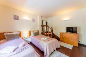 a bedroom with two beds and a dresser and a tv at Casa da Lagoa II in Terras de Bouro +37 photos