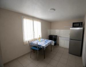 a kitchen with a table with chairs and a refrigerator at Appartement Coloquinte-Résidence Les Glycines in Eugénie-les-Bains
