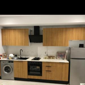 a kitchen with wooden cabinets and a stove and a refrigerator at Studio Hergla in Sidi Bou Ali