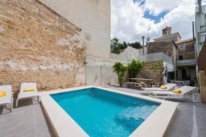 an outdoor swimming pool with chairs and a building at Villa Ca na Marrona - Sunset Villa Campanile in Sa Pobla