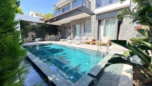 a swimming pool with chairs next to a building at Villa Maris Belek Villa in Belek