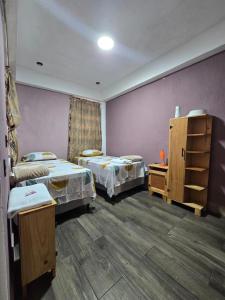 a room with two beds and a purple wall at Apartamento REFUGIO DEL LAGO in San Pedro La Laguna