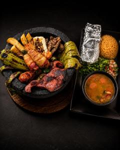a plate of food with meat and vegetables and a bowl of soup at Ramada by Wyndham Austin South in Austin