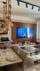 a living room with a table and a tv on a wall at Apt Icaraí Niterói Leonardo Davince in Niterói