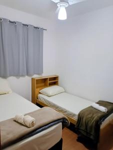 two twin beds in a room with a window at Apartamento 5 minutos do parque de exposições in Maringá