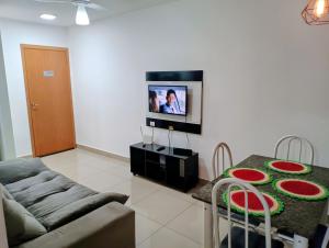 a living room with a couch and a table with a tv at Apartamento 5 minutos do parque de exposições in Maringá