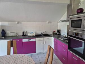 a kitchen with purple cabinets and a microwave at Gites les marronniers in Marigny