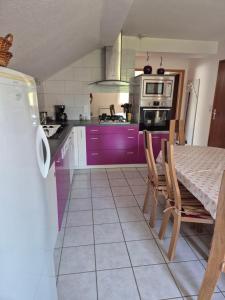 a kitchen with purple cabinets and a table with chairs at Gites les marronniers in Marigny