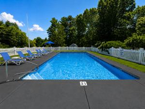 ein Swimmingpool mit Stühlen und einem weißen Zaun in der Unterkunft Cod Cove Inn, BW Signature Collection-Boothbay Harbor Area in Edgecomb