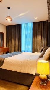 a bedroom with a large bed and a table with a lamp at Millennium Private Apartment in Salalah