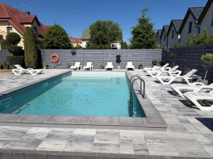 a swimming pool with chaise lounge chairs and a swimming pool at BalticMoon Rewal Domki z Podgrzewanym Basenem in Rewal