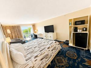 ein Hotelzimmer mit einem großen Bett und einem Fernseher in der Unterkunft Cod Cove Inn, BW Signature Collection-Boothbay Harbor Area in Edgecomb