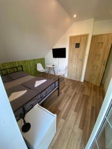 a room with a bed and a desk and a tv at House Hostelli in Grzybowo
