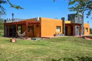 a house with a hammock in front of it at Cabañas Portal Uritorco in Capilla del Monte