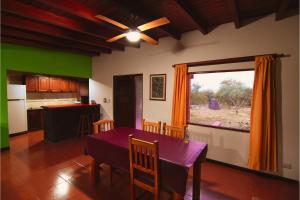a kitchen and dining room with a purple table and a window at Cabañas Portal Uritorco in Capilla del Monte